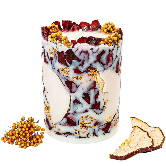 Handmade soy wax pillar candle with dried red apple slices, burgundy hydrangea petals and small golden flowers.