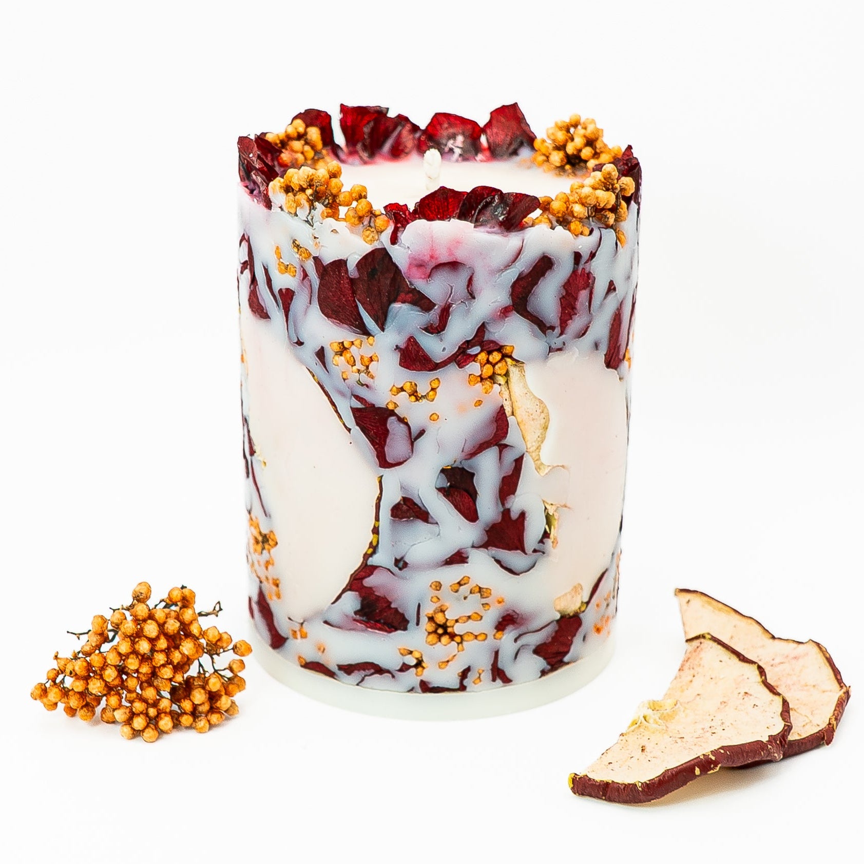 Hand-poured botanical pillar candle with dried hydrangea petals and red apple slices embedded in soy wax.