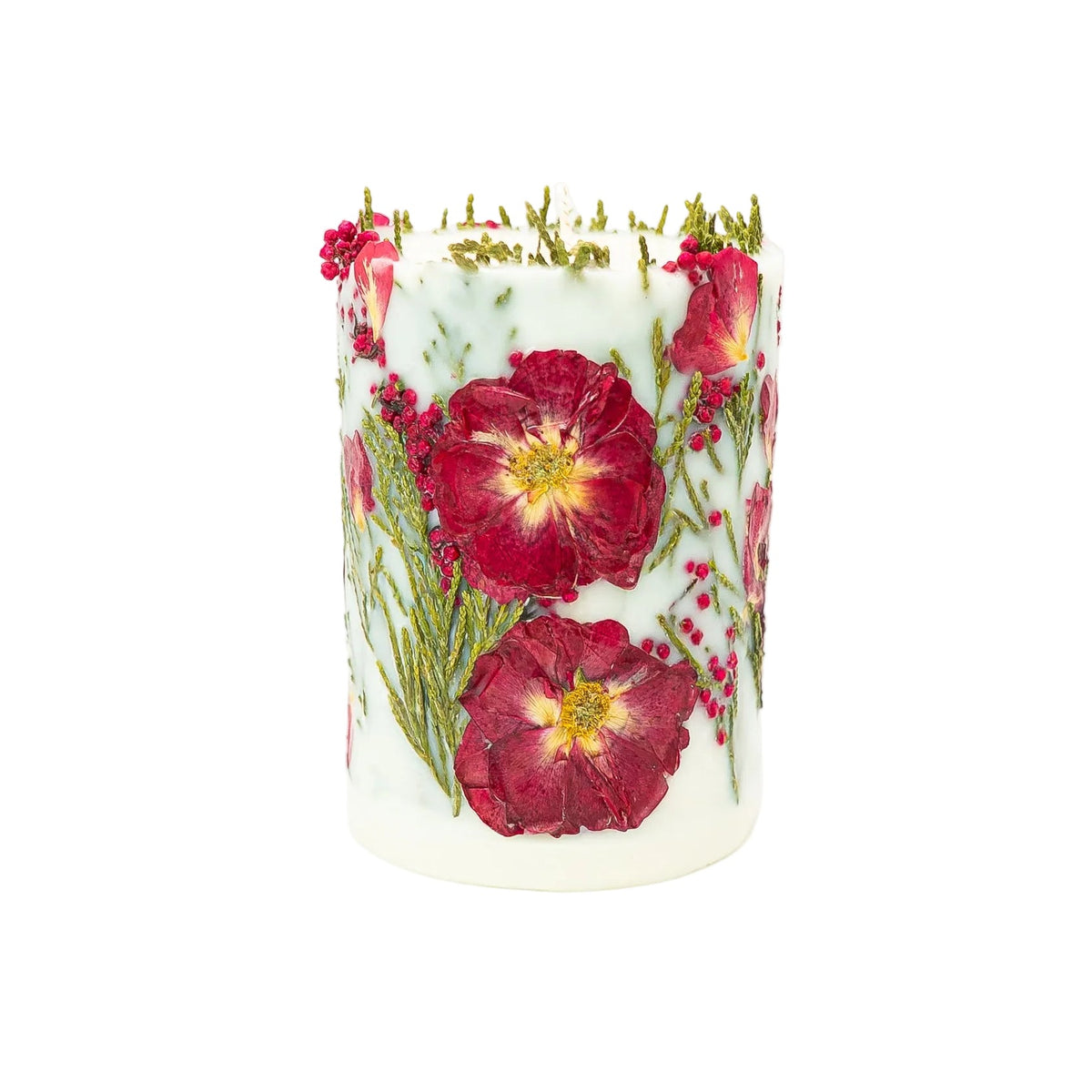 Two large dried red flowers pressed into the side of a white soy wax Christmas candle.