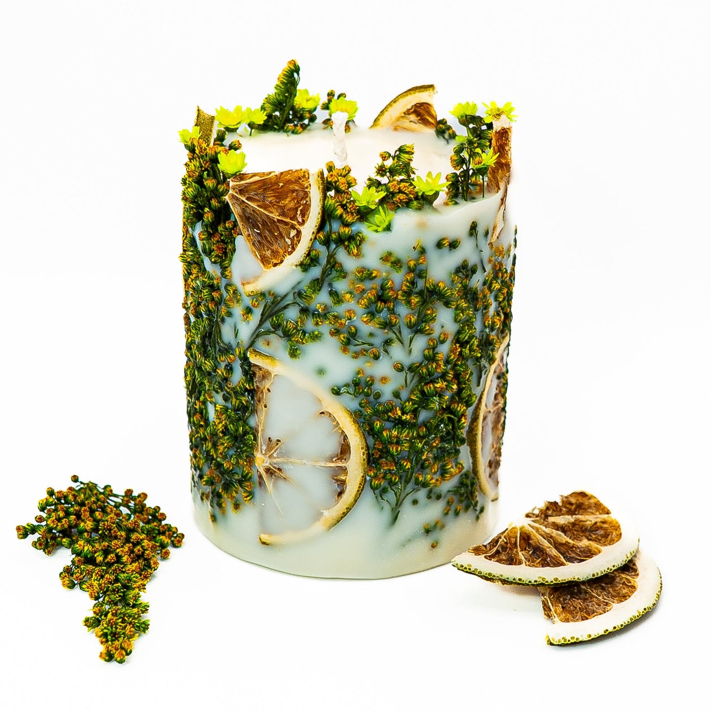 Rustic botanical pillar candle with dried citrus slices and natural greenery embedded in soy wax.