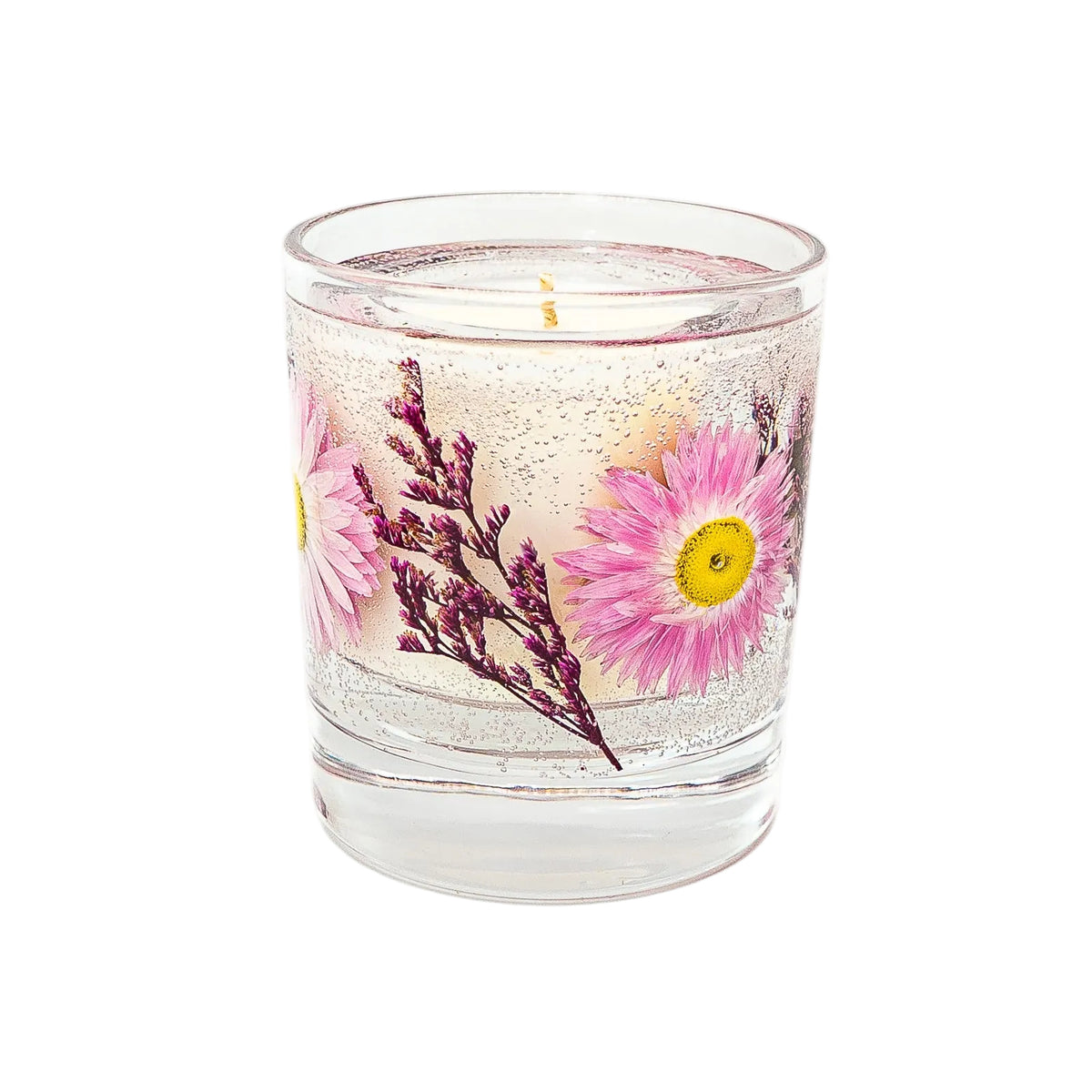 Side view of a botanical container candle with pink dried flowers and purple foliage set in gel wax around a soy wax centre.